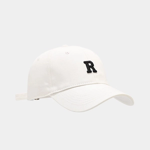 Detail view of white cotton baseball cap with black embroidered R letter patch