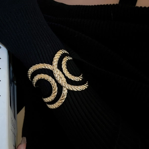 Close-up of golden twisted rope cuff bracelet with intertwined C design on black sleeve