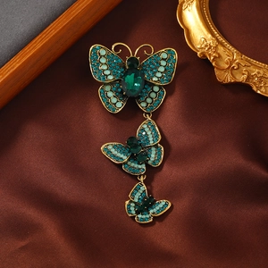 Macro detail of vintage gold butterfly brooch with green rhinestones on silk