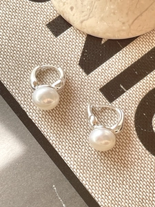 Detailed view of sterling silver hoop earrings featuring glossy white pearls for women