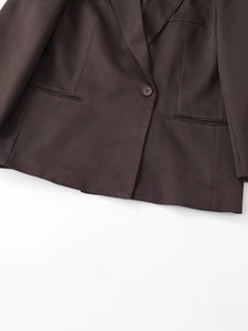 Dettaglio di un blazer marrone scuro con chiusura a bottone singolo e tasche piatte