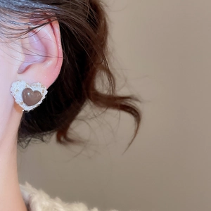 Detailed close-up of heart-shaped earrings featuring tweed fabric and resin inlay texture