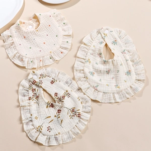 Detailed view of three 100% muslin cotton baby bibs with ruffles and snap buttons