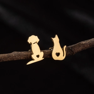 Macro view of gold cat and dog stud earrings resting on a rustic brown branch