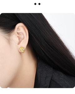 Detailed view of gold irregular textured earrings with small zircon stone on model
