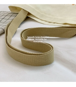 Close-up of the wide woven shoulder strap on a high-quality beige canvas tote bag