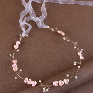 Detail of handmade bridal headband with pink fabric flowers and white pearl accents