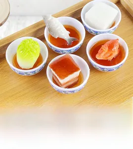 Detailed close-up of five miniature Chinese food models in blue and white porcelain bowls