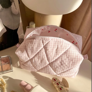 Pink checkered quilted cotton cosmetic bag with cherry lining on a vanity table