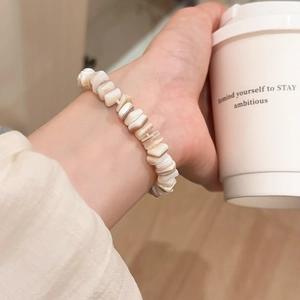 Close-up of irregular shell bead bracelet on wrist with a warm minimalist aesthetic