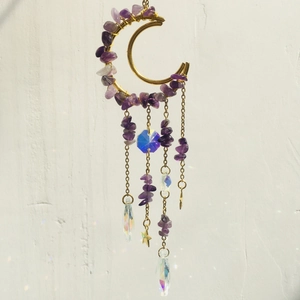 Detail of amethyst moon suncatcher showing rainbow light refraction on white wall
