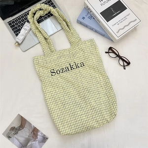 Flat lay of yellow checkered canvas tote bag with Sozakka logo and daily lifestyle items