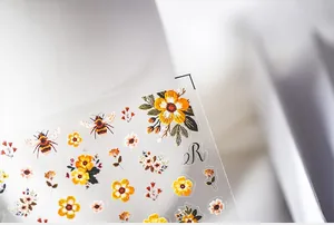 Detailed macro view of 5D floral embroidery nail stickers with yellow flowers and bees
