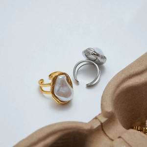 Close-up of gold and silver titanium rings featuring unique baroque pearls in gift box
