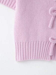 Close-up of pink knit top featuring ribbed hem and side-tie ribbon detail