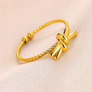 Detailed macro view of a gold-plated twisted rope ring featuring a unique knot design element
