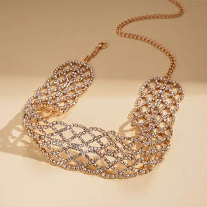 Close-up of golden geometric mesh necklace with pavé crystal accents and hollow design