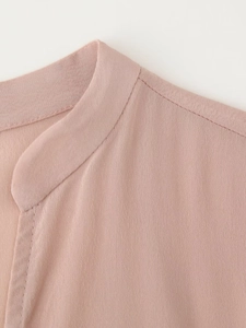 Dettaglio della camicia in raso di seta rosa con elegante scollo a V e trama del tessuto