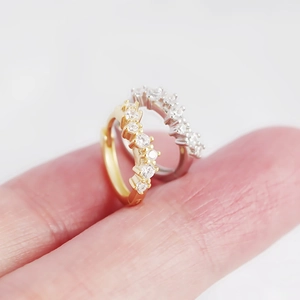 Macro shot of small gold and silver huggie earrings with cubic zirconia on fingertips