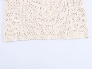 Detailed macro view of the cream-colored crochet lace fabric with hollow floral patterns