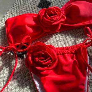 Detail of red bikini with 3D rose flower accents on tube top and side-tie bottoms