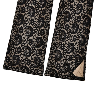 Détail du pantalon en dentelle paisley noire avec doublure beige et fente latérale