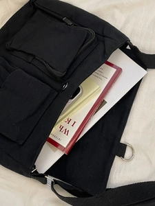 Black canvas crossbody bag with multiple pockets showing interior storage space