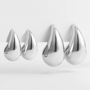 Close-up detail of two pairs of polished silver stainless steel teardrop earrings