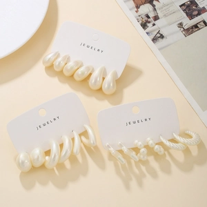 Close-up of assorted white pearl-finish acrylic hoop earrings on jewelry display cards