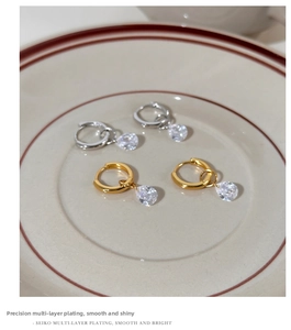 Detail showing polished gold and silver hoop earrings with teardrop zircon charms