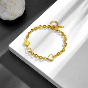 Elegant gold stainless steel bracelet with white shell heart and clover charms on white platform