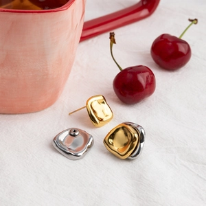 Close-up of irregular geometric stainless steel earrings in gold and silver finish