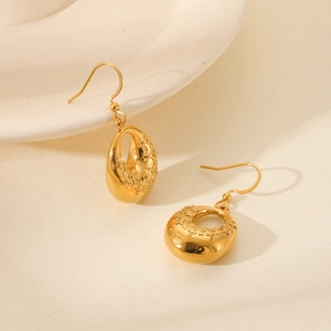 Macro detail of 18K gold teardrop earrings featuring intricate engraved palace patterns