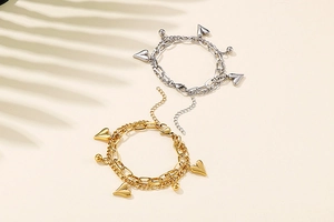 Detail of double-layer heart bracelet in gold and silver finish with ball charms