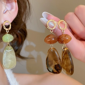 Detail of vintage irregular resin drop earrings with gold textured metal hoops