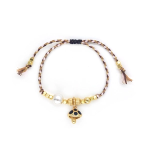 Detail of bohemian woven bracelet with a gold mushroom charm and white pearl accent