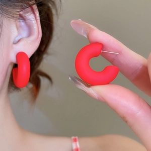 Close-up of red matte acrylic C-shaped hoop earrings with silver pins for women