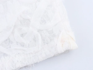 Dettaglio macro del tessuto in pizzo floreale bianco e trama a rete del vestito