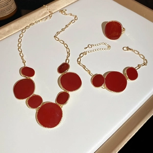 Détail d'ensemble de bijoux en émail rouge et métal doré avec collier bracelet et bague