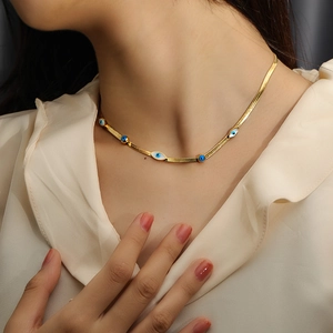 Elegant gold plated snake chain necklace with blue evil eye charms on a female model