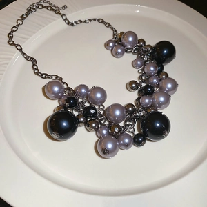 Detail of irregular black pearl necklace with tassel pendant in edgy dark aesthetic