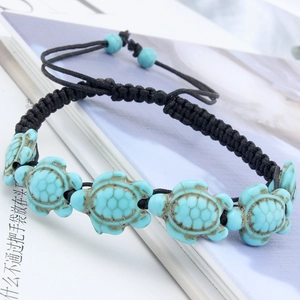 Detailed macro shot of blue turquoise turtle charms on a black braided cord bracelet