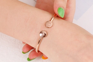 Detail of rose gold open bangle featuring tree of life and Hope engraving on wrist
