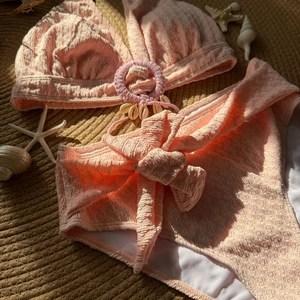 Detail of seashell charm and textured seersucker fabric on a pink high waist bikini