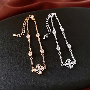 Gold and silver flower bracelets with clover zircon accents on a textured surface