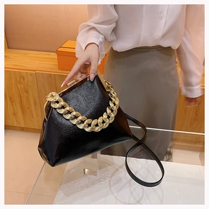 Close-up of black textured leather handbag with gold chain handle and vintage clasp