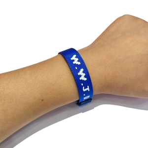 Close-up of blue woven WWJD bracelet with white embroidery and adjustable black buckle