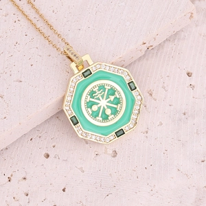 Detail of gold octagon pendant with green enamel and crystal inlay on stone surface