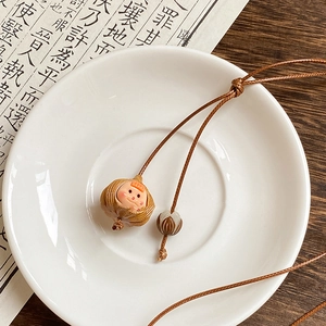 Detail of nut shell pendant with cartoon girl inside on brown adjustable cord necklace