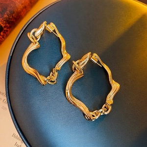 Irregular twisted gold earrings with woven texture on a blue leather display box